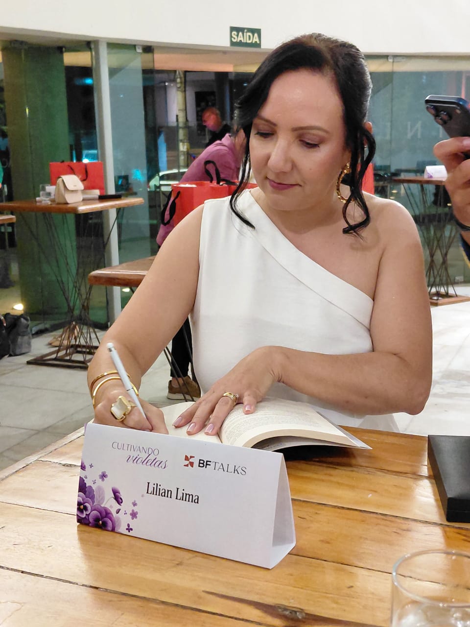 Lilian Lima dedicando o livro Cultivando Violetas durante sessão de autógrafos